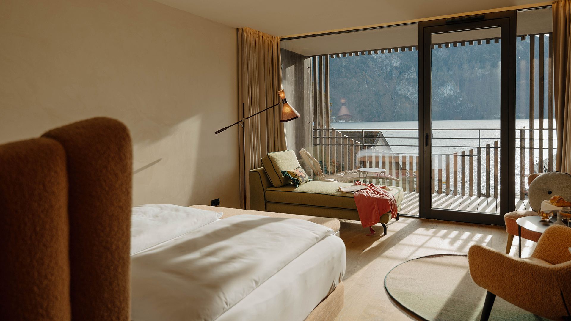 Heavenly Lake Junior Suite in der Post am See mit Doppelbett, Sitzecke und Blick Richtung Balkon und Traunsee.