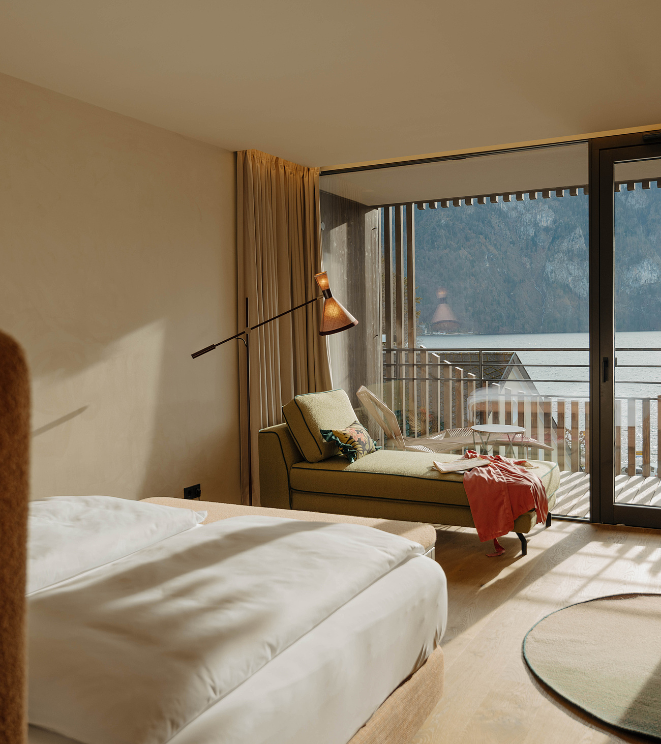 Heavenly Lake Junior Suite in der Post am See mit Doppelbett, Sitzecke und Blick Richtung Balkon und Traunsee.