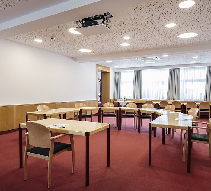 Seminarraum mit U-förmiger Bestuhlung, Präsentationstechnik und großen Fensterflächen.