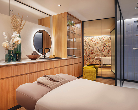 Innenansicht des Beauty- und Massagebereichs mit hellbraunen Holzmöbeln und Massageliege.