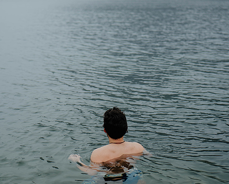 Mann beim Eisbaden im Traunsee, der den Ausblick auf die Berge genießt