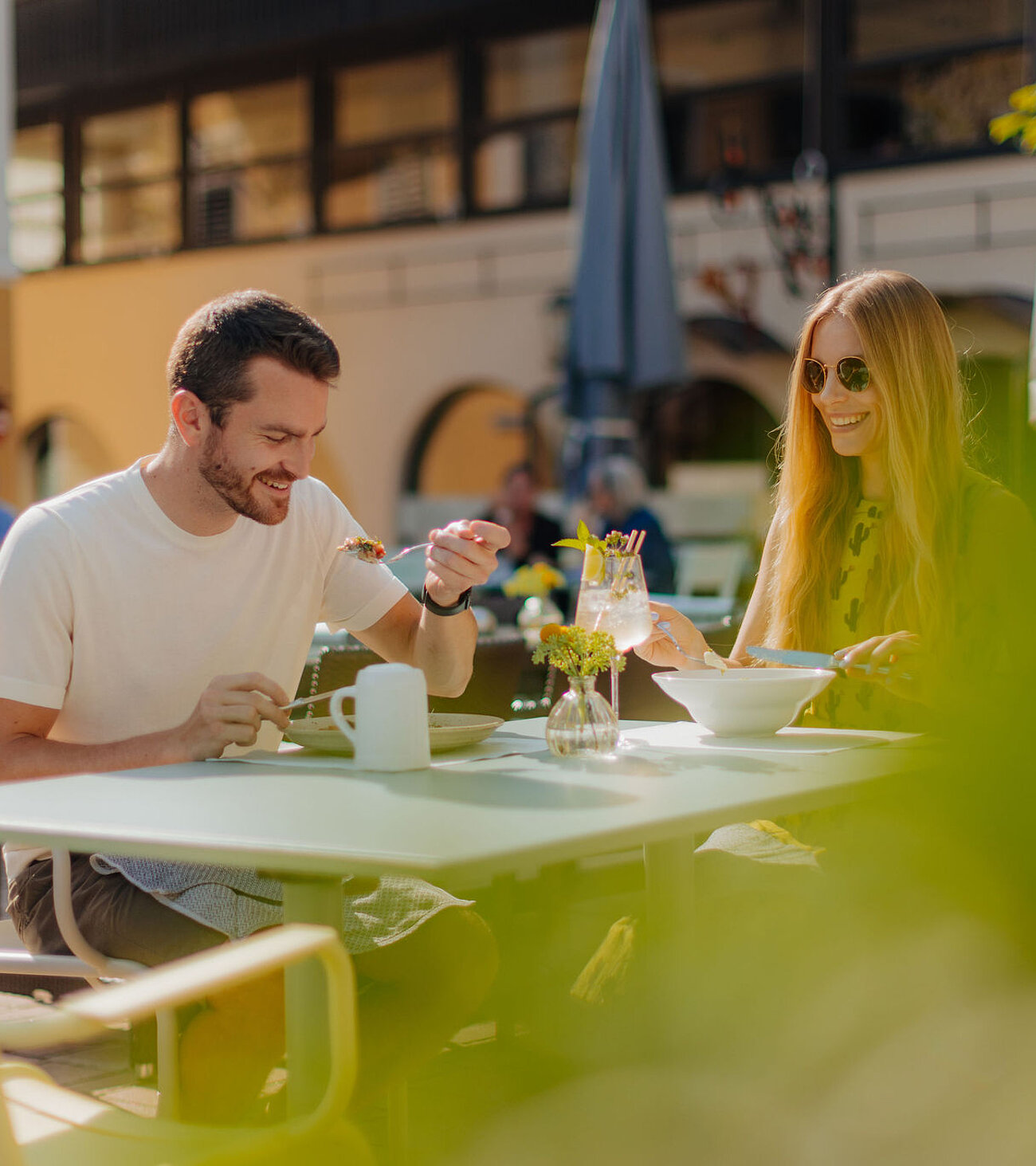 Gastgarten im Sommer mit einem Pärchen beim Essen, im Hintergrund unser Hotel