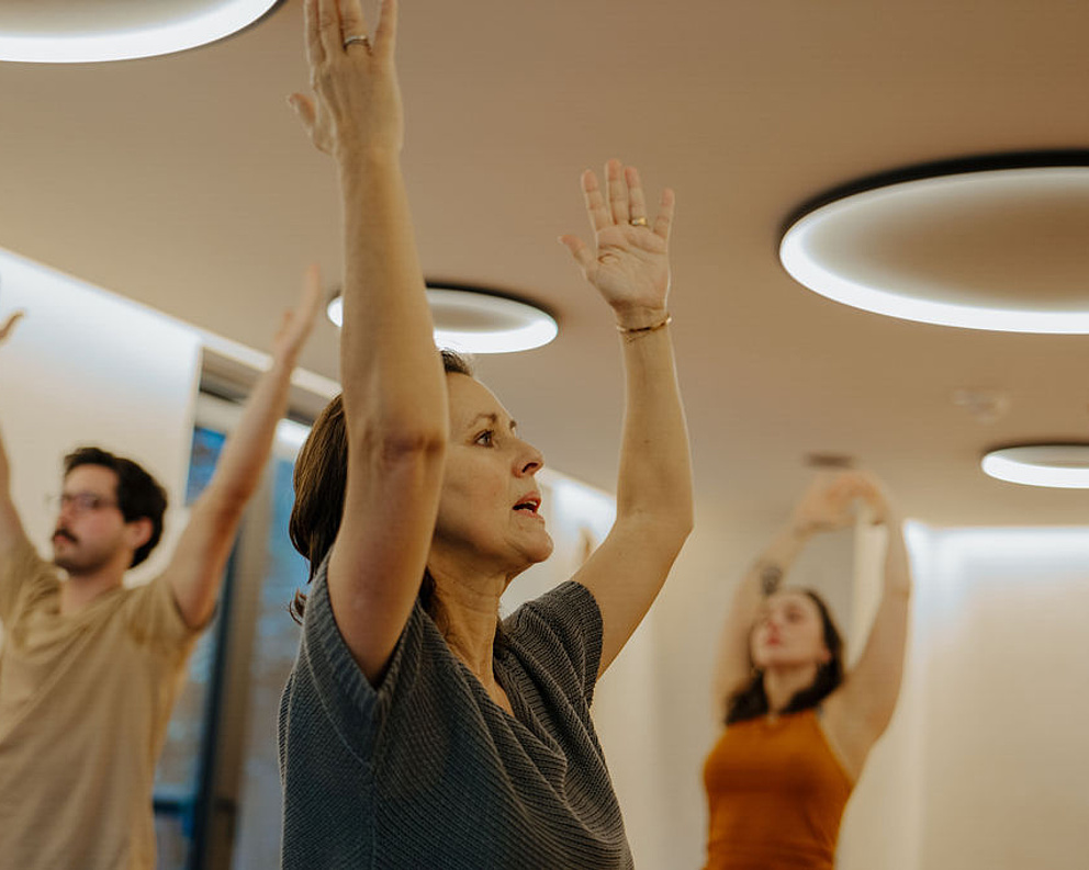 Teilnehmer bei einer Yoga-Session mit erhobenen Händen