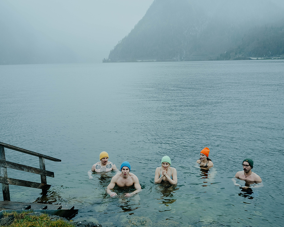 Fünf Gäste beim Eisbaden im Traunsee – im kalten Wasser, frierend, aber entschlossen. Winterliche, neblige Atmosphäre