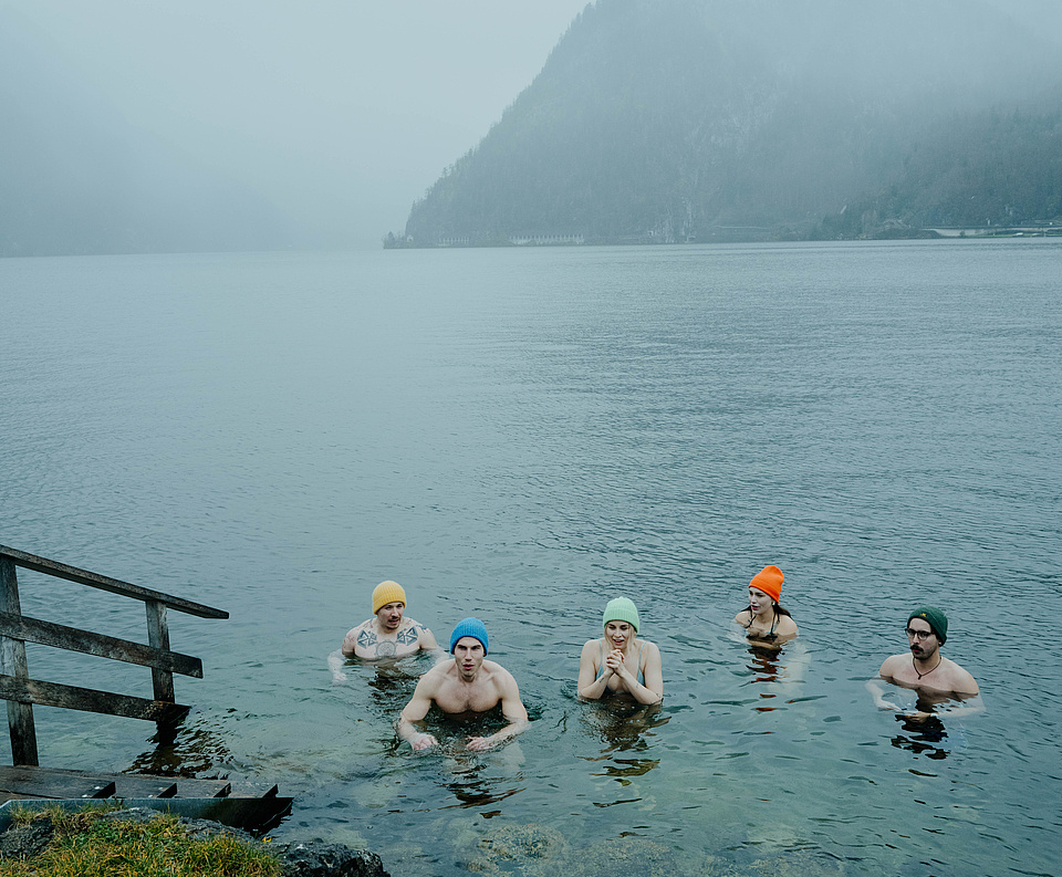 Fünf Gäste beim Eisbaden im Traunsee – im kalten Wasser, frierend, aber entschlossen. Winterliche, neblige Atmosphäre