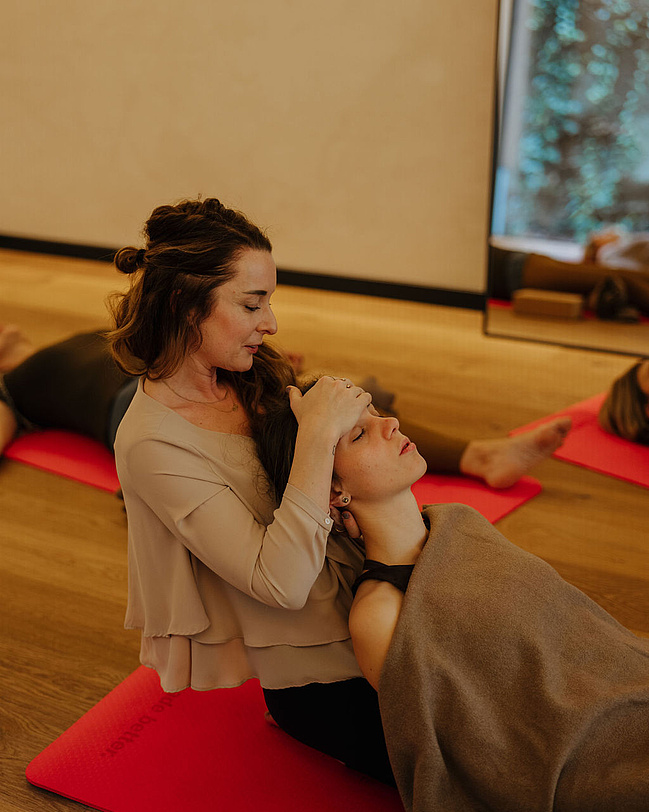 Gäste bei einer Breathwork-Session, während die Coachin einem Gast bei einer Übung hilft