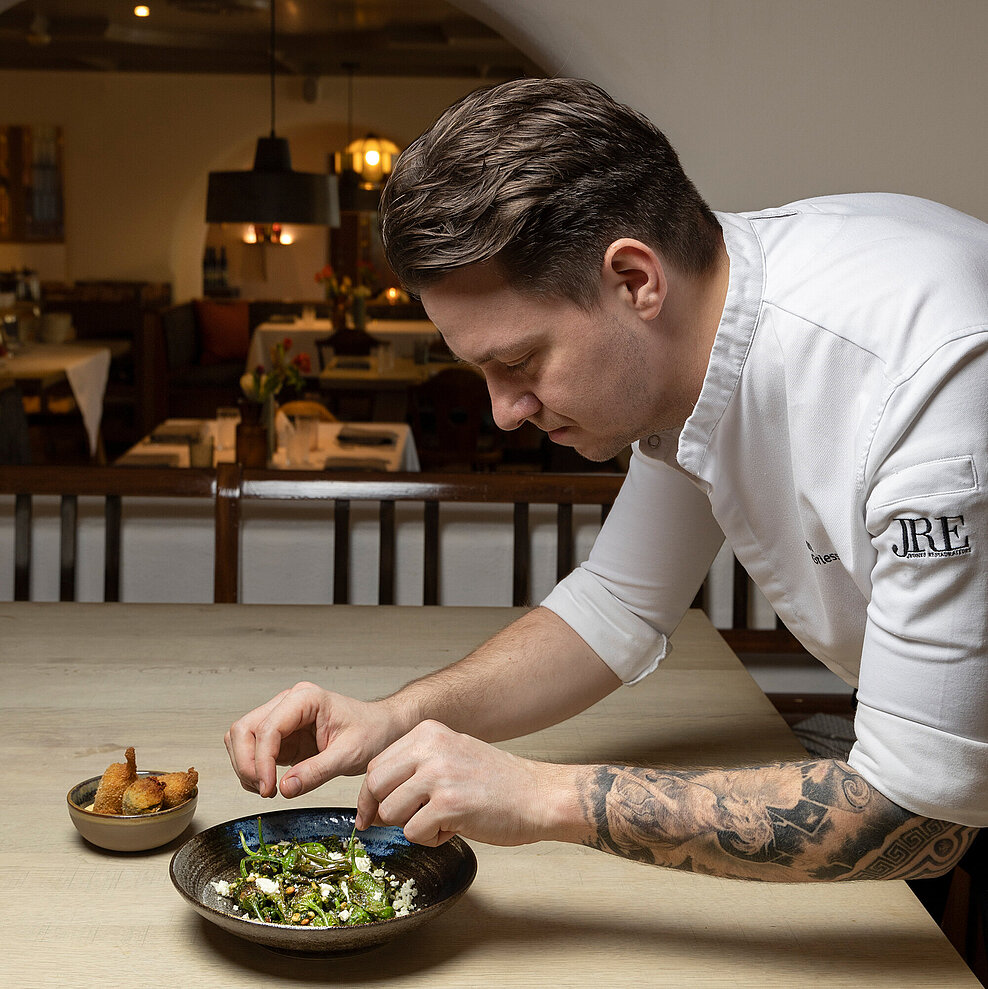 Küchenchef richtet Pimientos Padron am Restauranttisch an