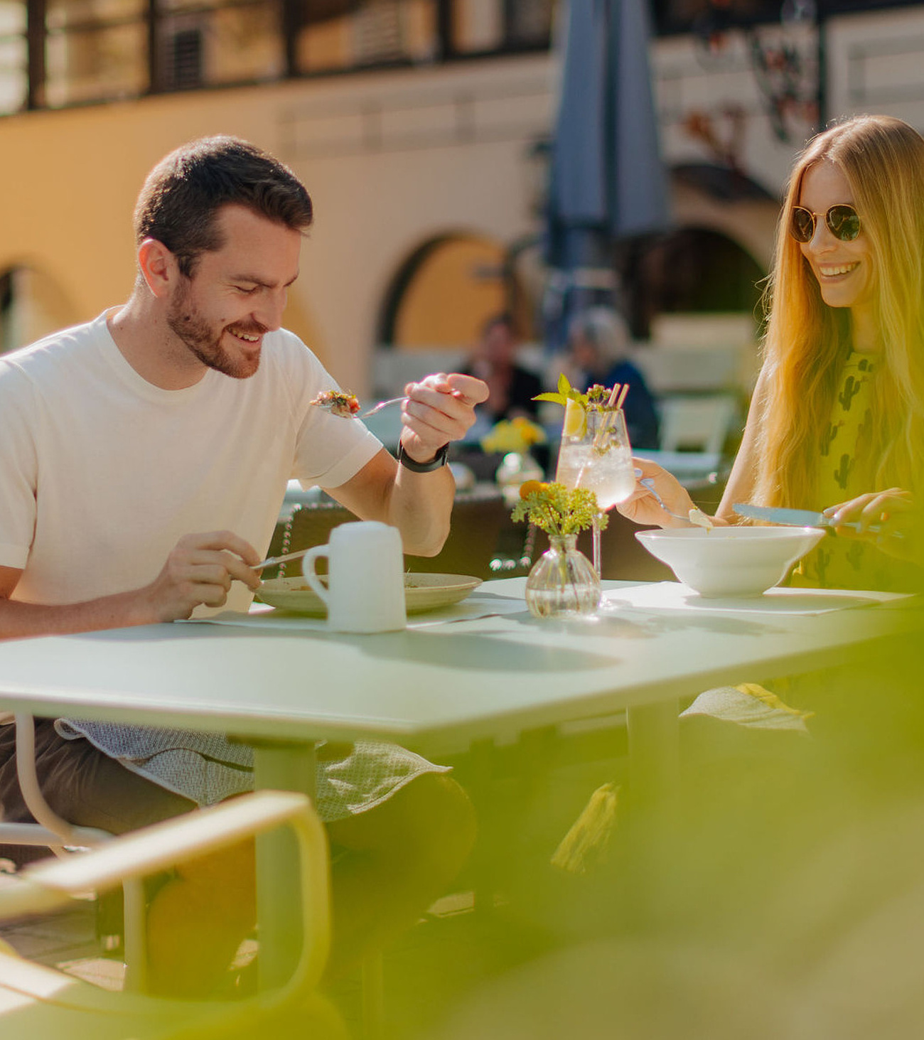 Gastgarten im Sommer mit einem Pärchen beim Essen, im Hintergrund unser Hotel