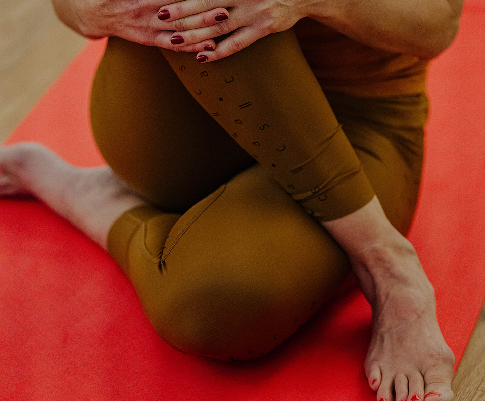 Person in sitzender Yogapose auf einer roten Matte