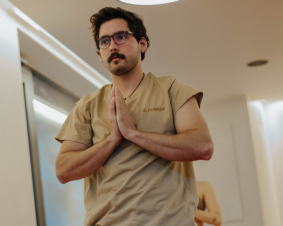 Mann steht in einer Yoga-Pose im Yogaraum
