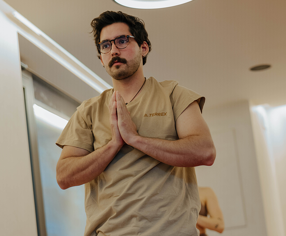 Mann steht in einer Yoga-Pose im Yogaraum