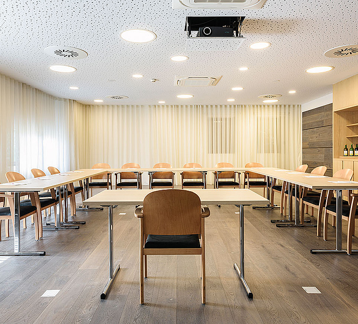 Heller Seminarraum mit U-förmiger Bestuhlung, Präsentationstechnik und moderner Ausstattung.