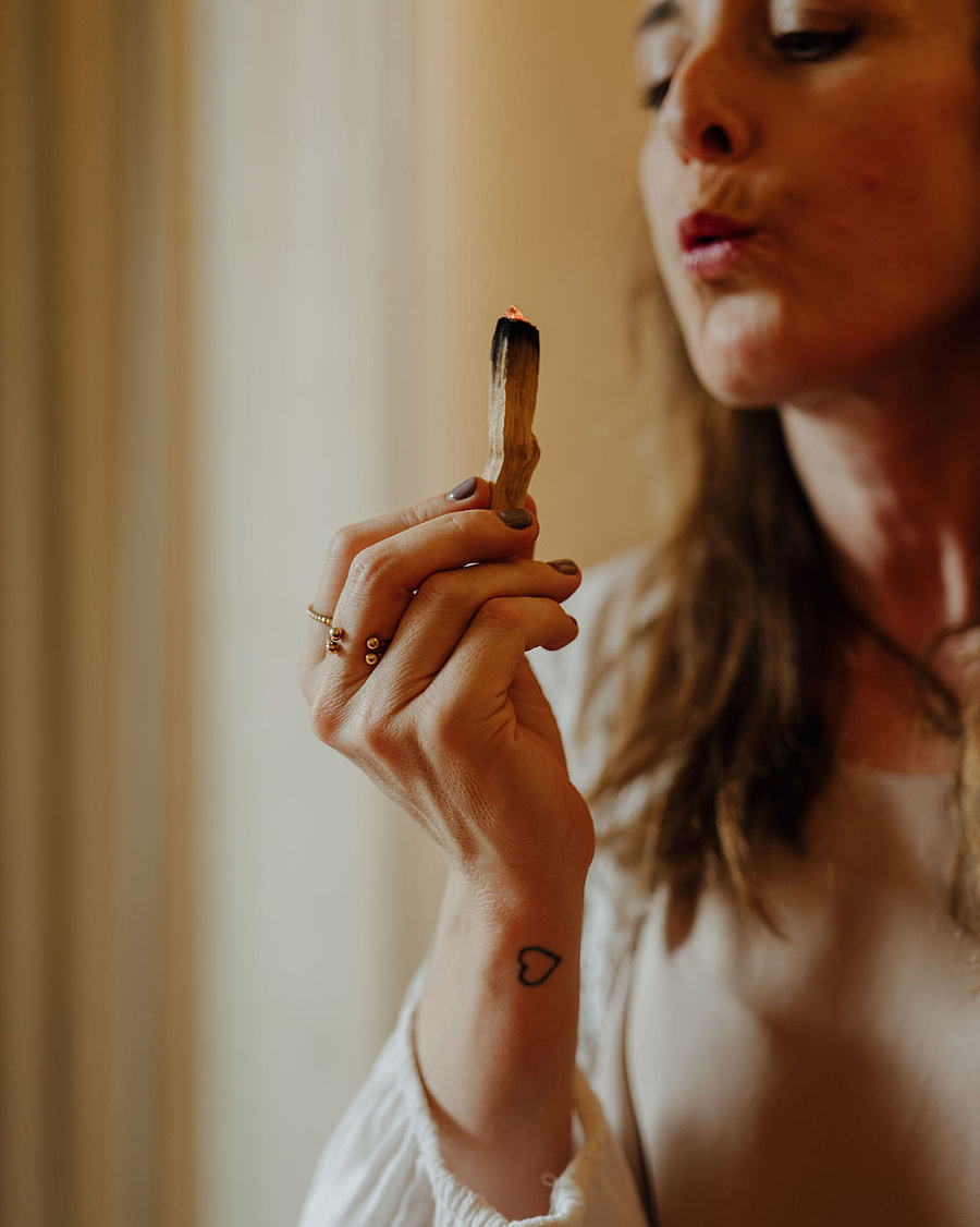 Breathwork-Coachin bläst sanft den Rauch eines Räucherholzes aus