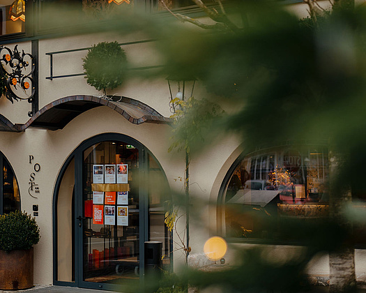 Eingangsbereich des Hotels mit darüberliegenden Fenstern des Restaurants Beletage, durch grüne Zweige hindurch fotografiert