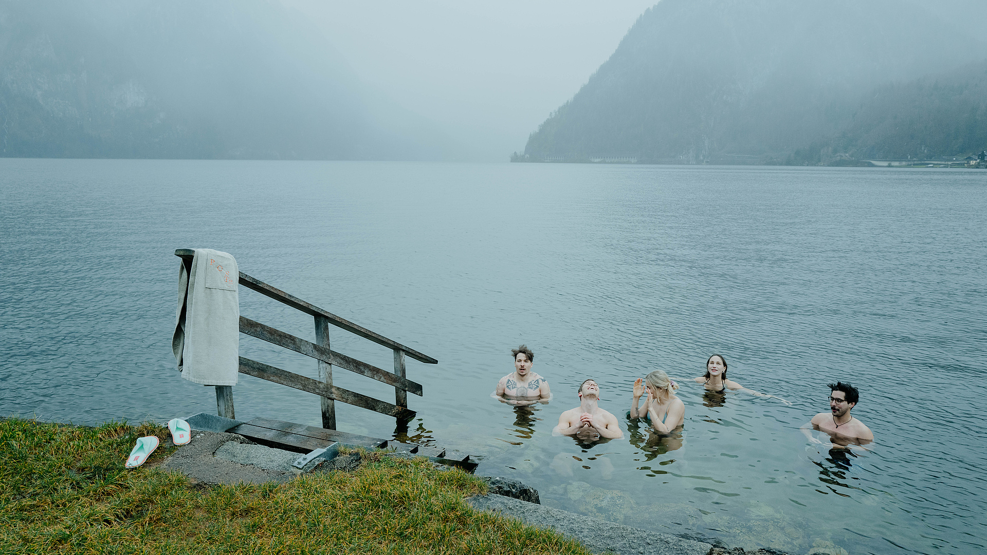Fünf Gäste beim Eisbaden im Traunsee – lächelnd im kalten Wasser, umgeben von Nebel und winterlicher Atmosphäre