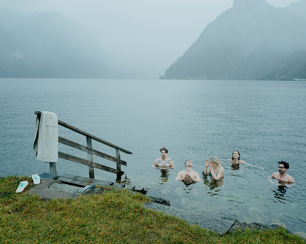 Fünf Gäste beim Eisbaden im Traunsee – lächelnd im kalten Wasser, umgeben von Nebel und winterlicher Atmosphäre