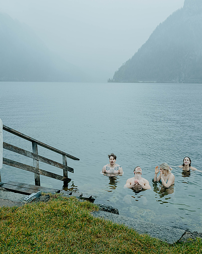 Fünf Gäste beim Eisbaden im Traunsee – lächelnd im kalten Wasser, umgeben von Nebel und winterlicher Atmosphäre