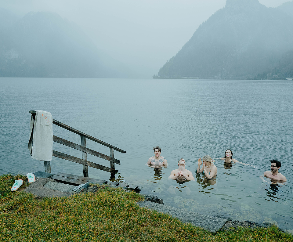 Fünf Gäste beim Eisbaden im Traunsee – lächelnd im kalten Wasser, umgeben von Nebel und winterlicher Atmosphäre