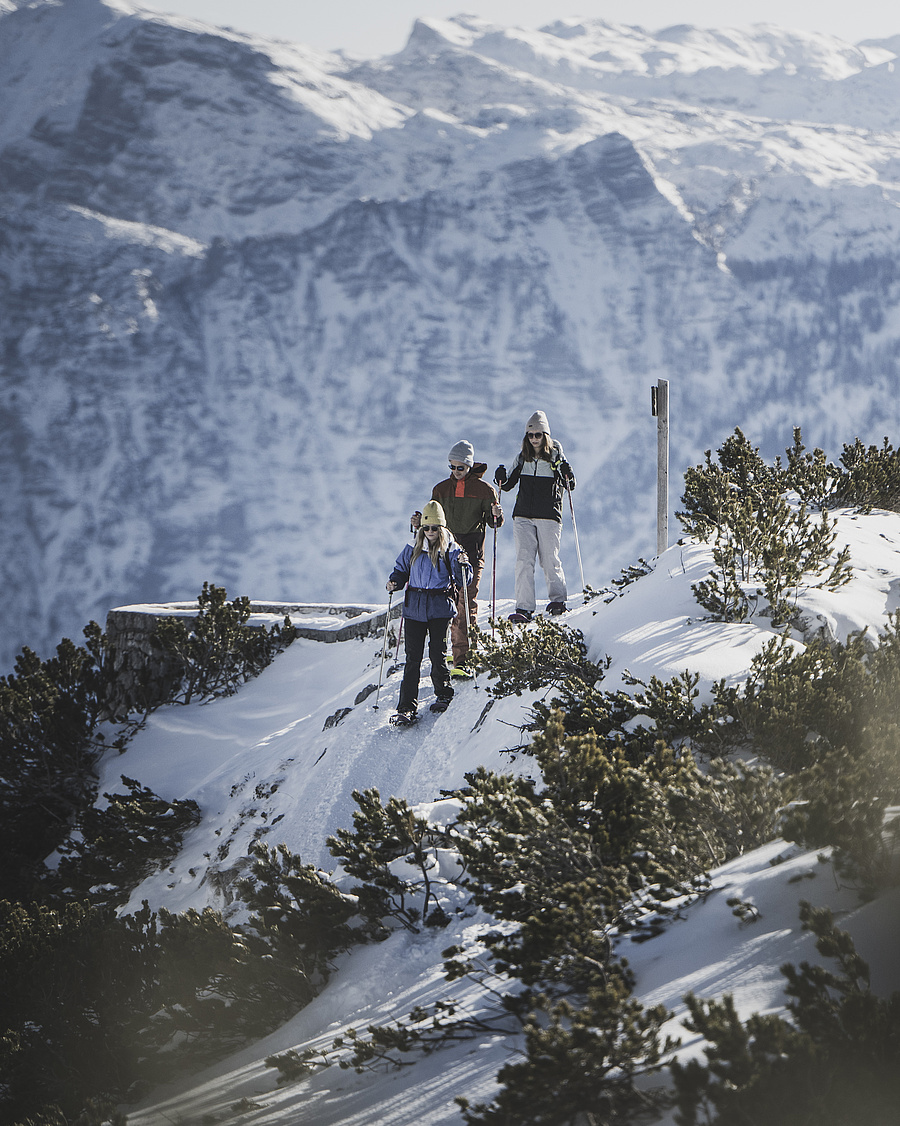 Drei Personen mit Schneeschuhen wandern durch die verschneite Berglandschaft am Feuerkogel
