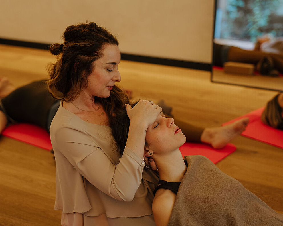 Gäste bei einer Breathwork-Session, während die Coachin einem Gast bei einer Übung hilft