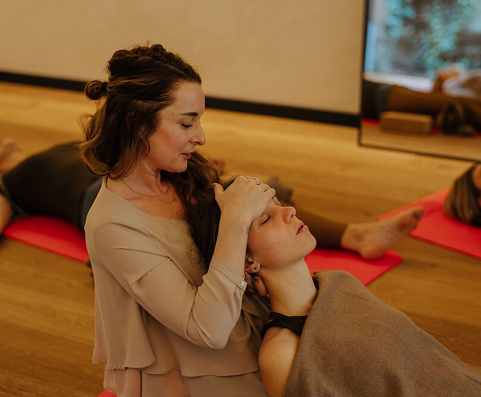Gäste bei einer Breathwork-Session, während die Coachin einem Gast bei einer Übung hilft