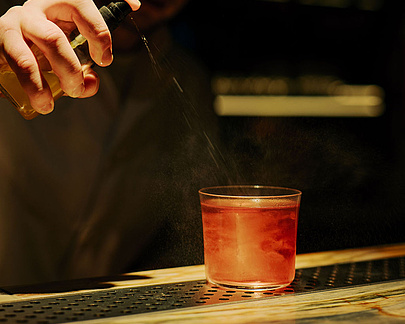 Cocktail wird vom Barkeeper im dunklen Ambiente des Restaurants Beletage hergerichtet
