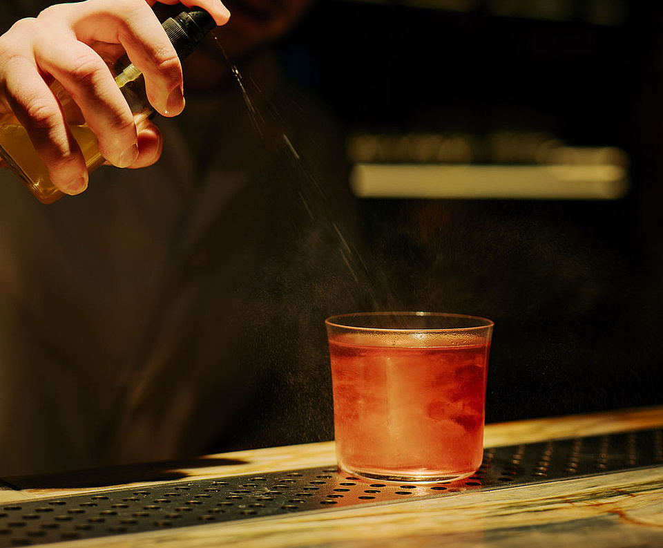 Cocktail wird vom Barkeeper im dunklen Ambiente des Restaurants Beletage hergerichtet