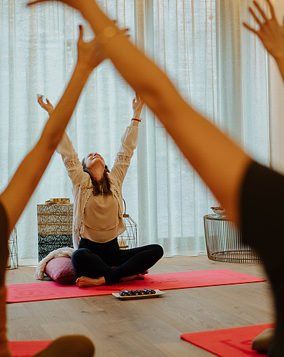 Gäste bei einer Breathwork-Session mit der Coachin vor einem offenen Fenster im Yogaraum