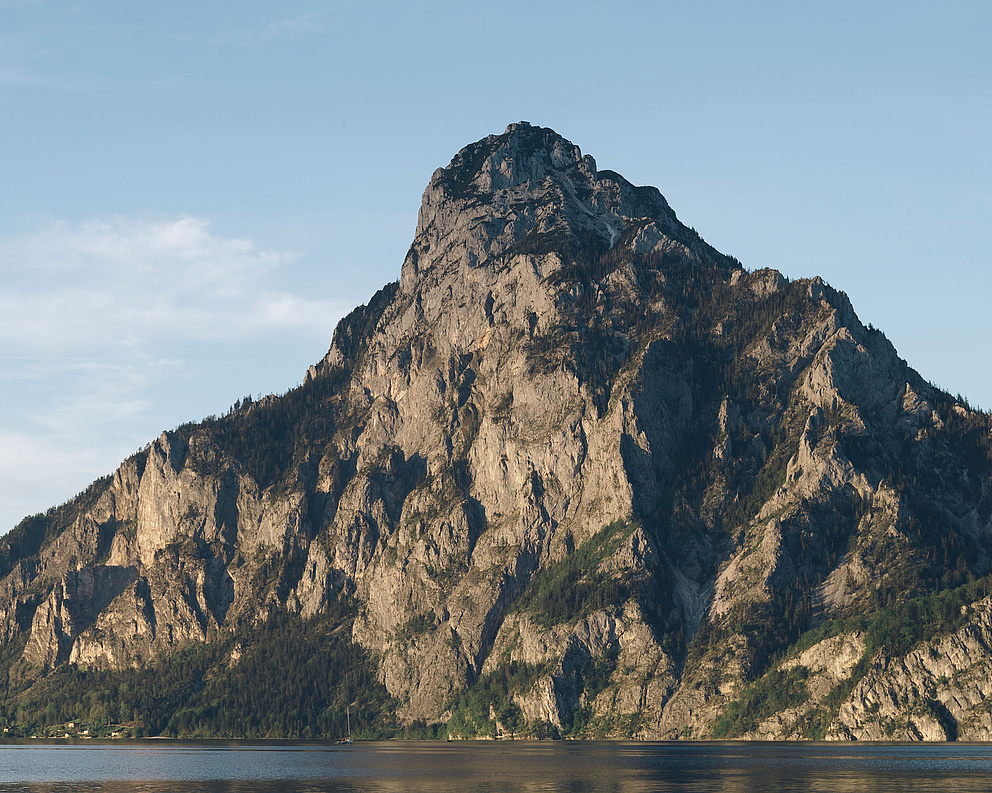 Plätte mit Fischern auf dem Traunsee, im Hintergrund der Traunstein und blauer Himmel.