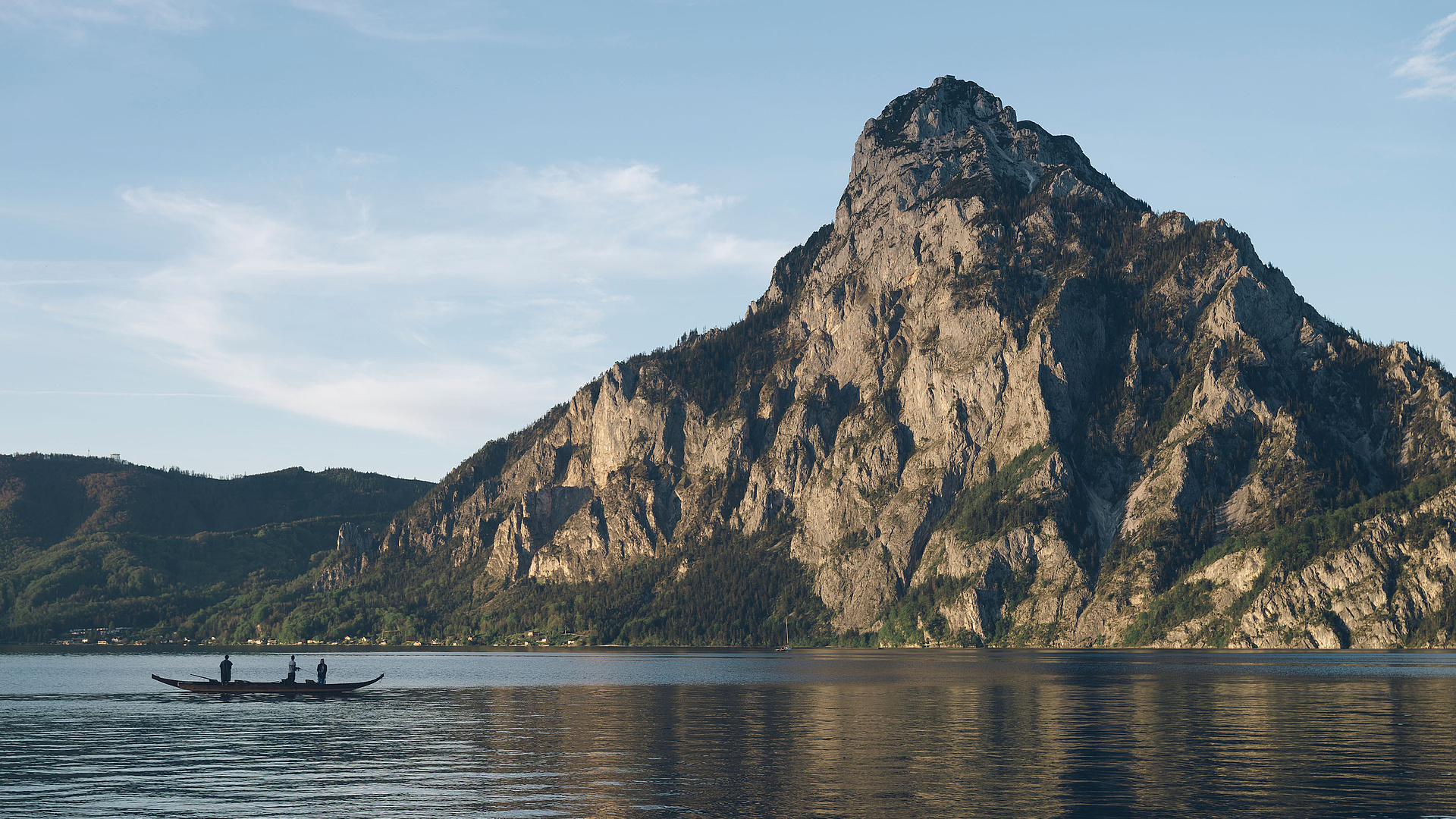 Plätte mit Fischern auf dem Traunsee, im Hintergrund der Traunstein und blauer Himmel.