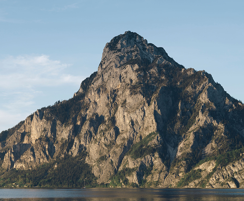 Plätte mit Fischern auf dem Traunsee, im Hintergrund der Traunstein und blauer Himmel.