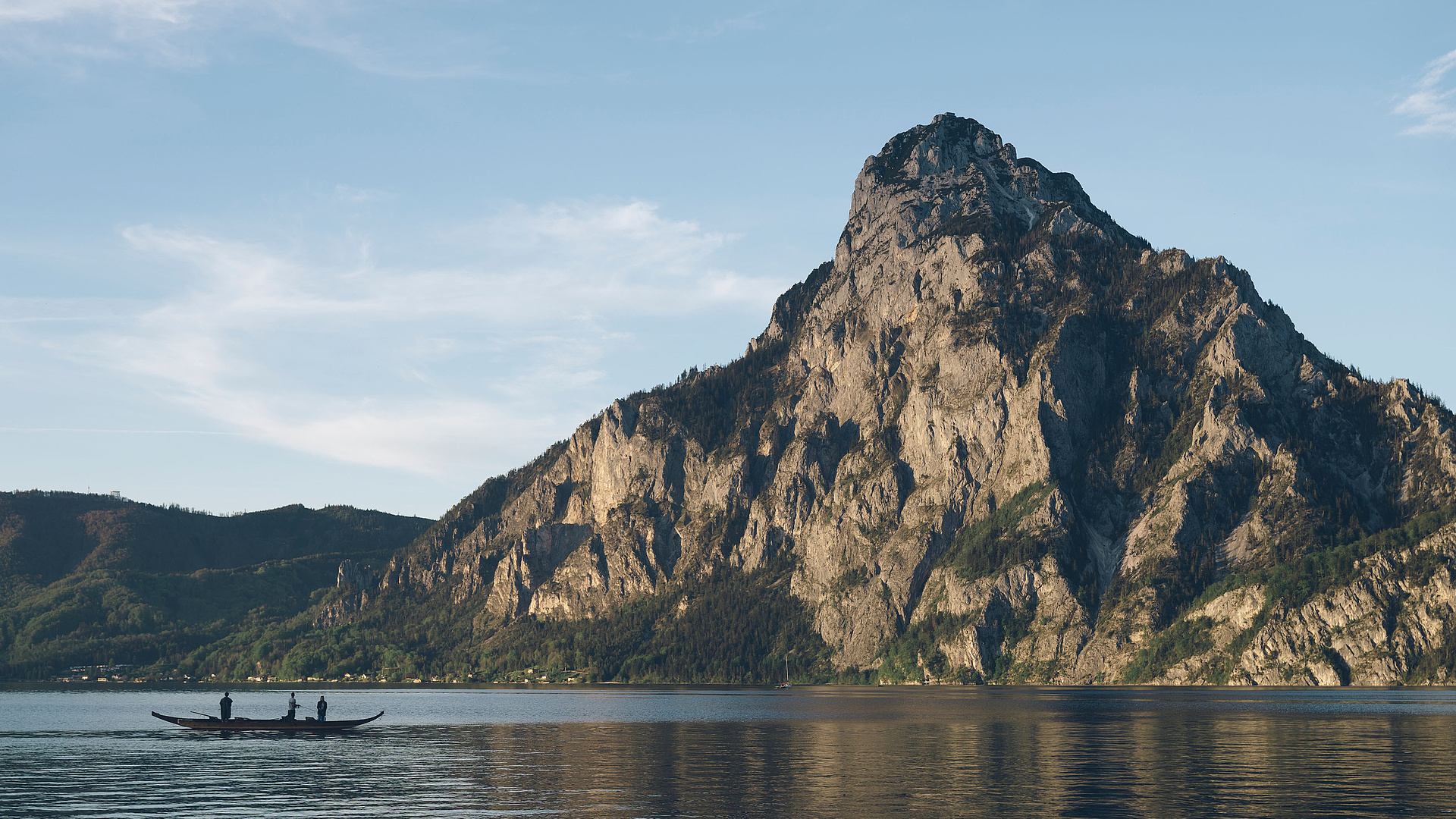 Plätte mit Fischern auf dem Traunsee, im Hintergrund der Traunstein und blauer Himmel.