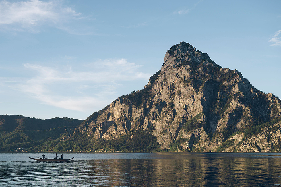 Plätte mit Fischern auf dem Traunsee, im Hintergrund der Traunstein und blauer Himmel.