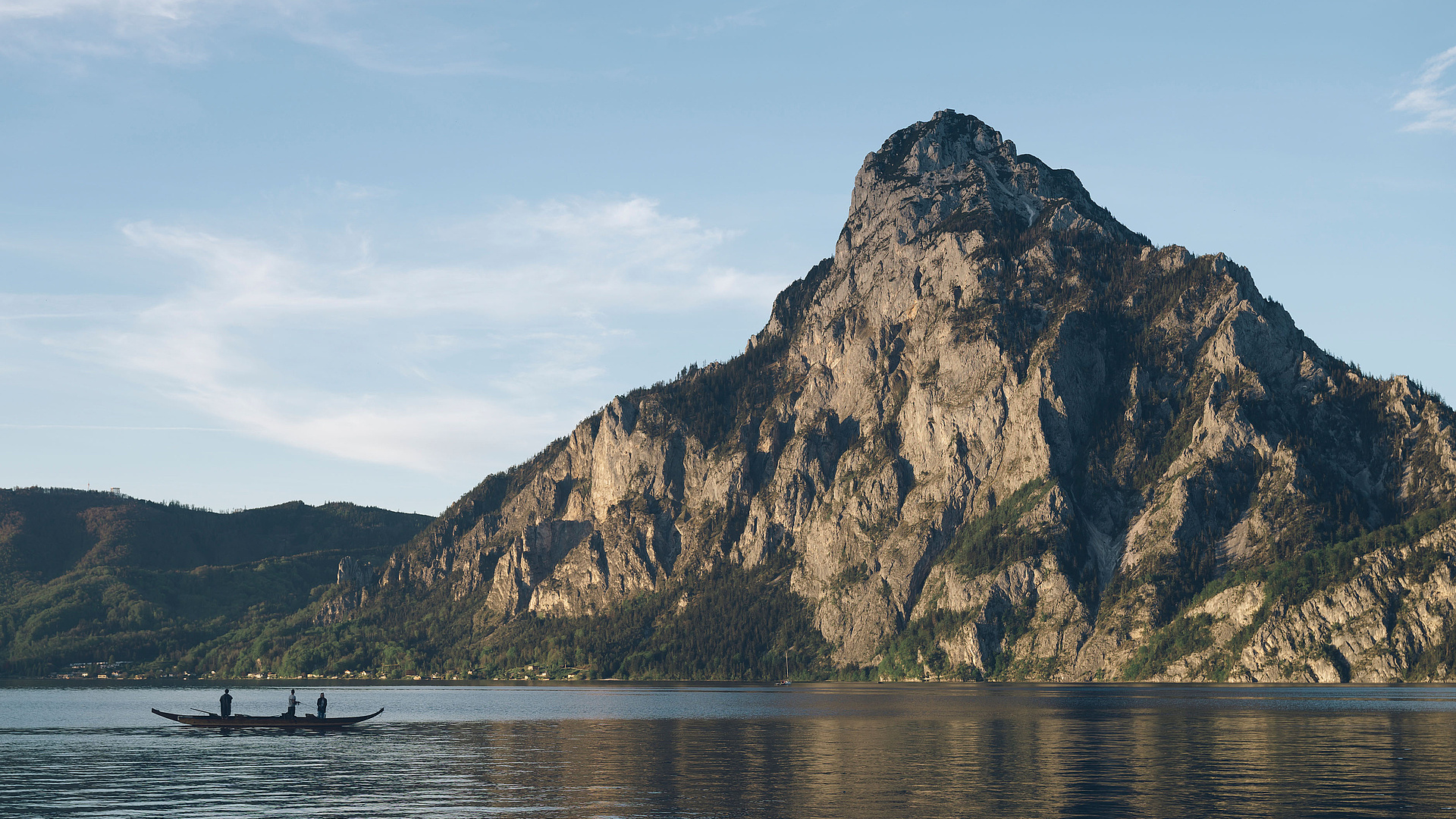Plätte mit Fischern auf dem Traunsee, im Hintergrund der Traunstein und blauer Himmel.