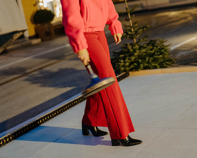 Frau beim Eisstockschießen auf der Eisstockbahn vor unserem Hotel, im Hintergrund das Hotel und die Greisslerei
