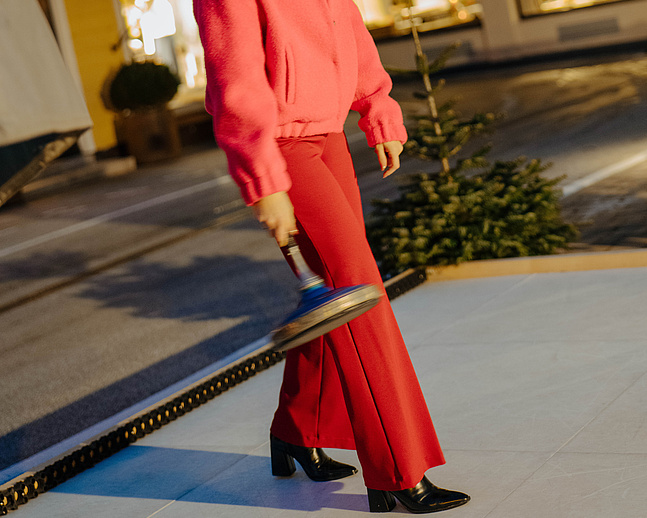 Frau beim Eisstockschießen auf der Eisstockbahn vor unserem Hotel, im Hintergrund das Hotel und die Greisslerei