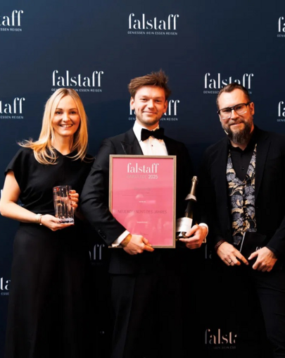 Chef de Bar Markus hält die Falstaff-Auszeichnung für die "Bar des Jahres 2025" in der Hand, mit der blauen Falstaff-Werbung im Hintergrund.