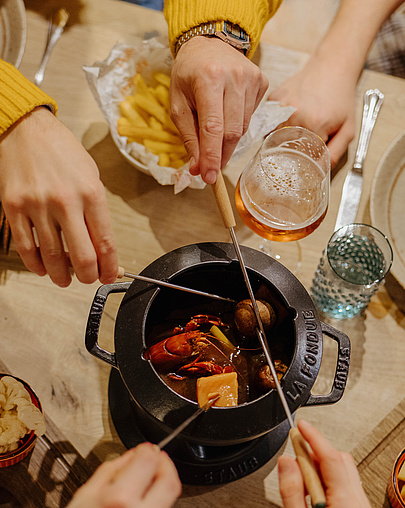 Draufsicht auf vier Personen beim Fondue-Essen in der Poststube 1327
