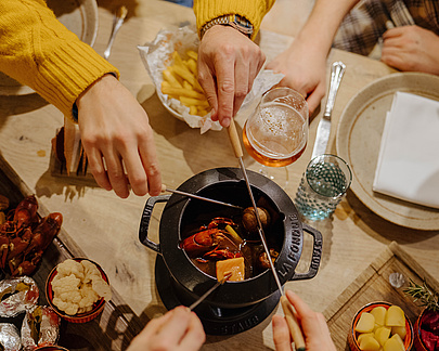 Draufsicht auf vier Personen beim Fondue-Essen in der Poststube 1327