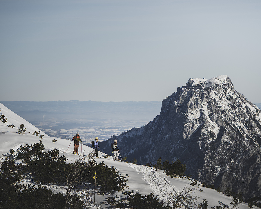 Drei Gäste mit Schneeschuhen wandern in den Bergen, mit dem Traunstein im Hintergrund