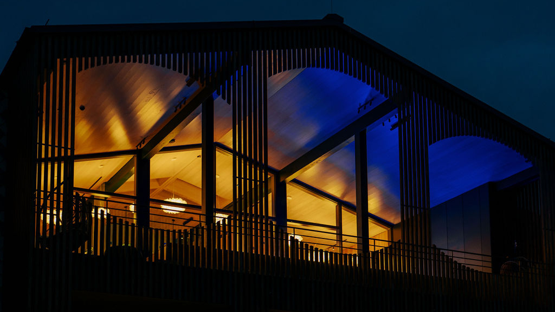 Nachtaufnahme vom Spa-Bereich im 6. Stock mit Holzverkleidung und goldenem Licht, reflektierendes blaues Licht des Außenpools
