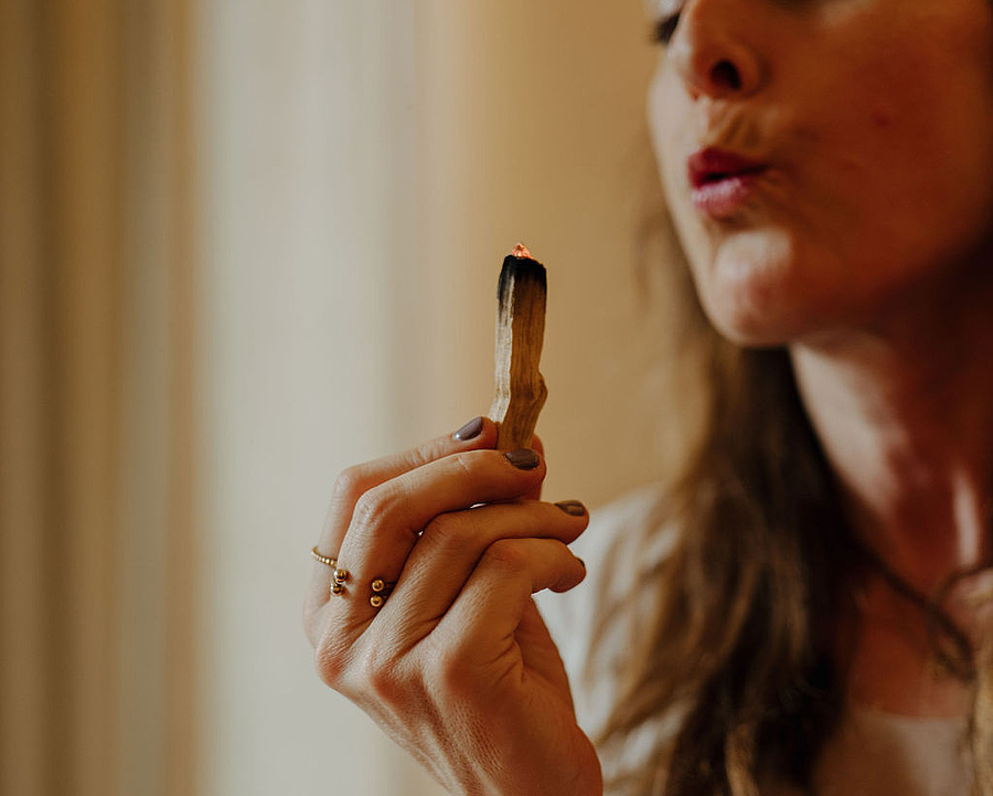 Breathwork-Coachin bläst sanft den Rauch eines Räucherholzes aus