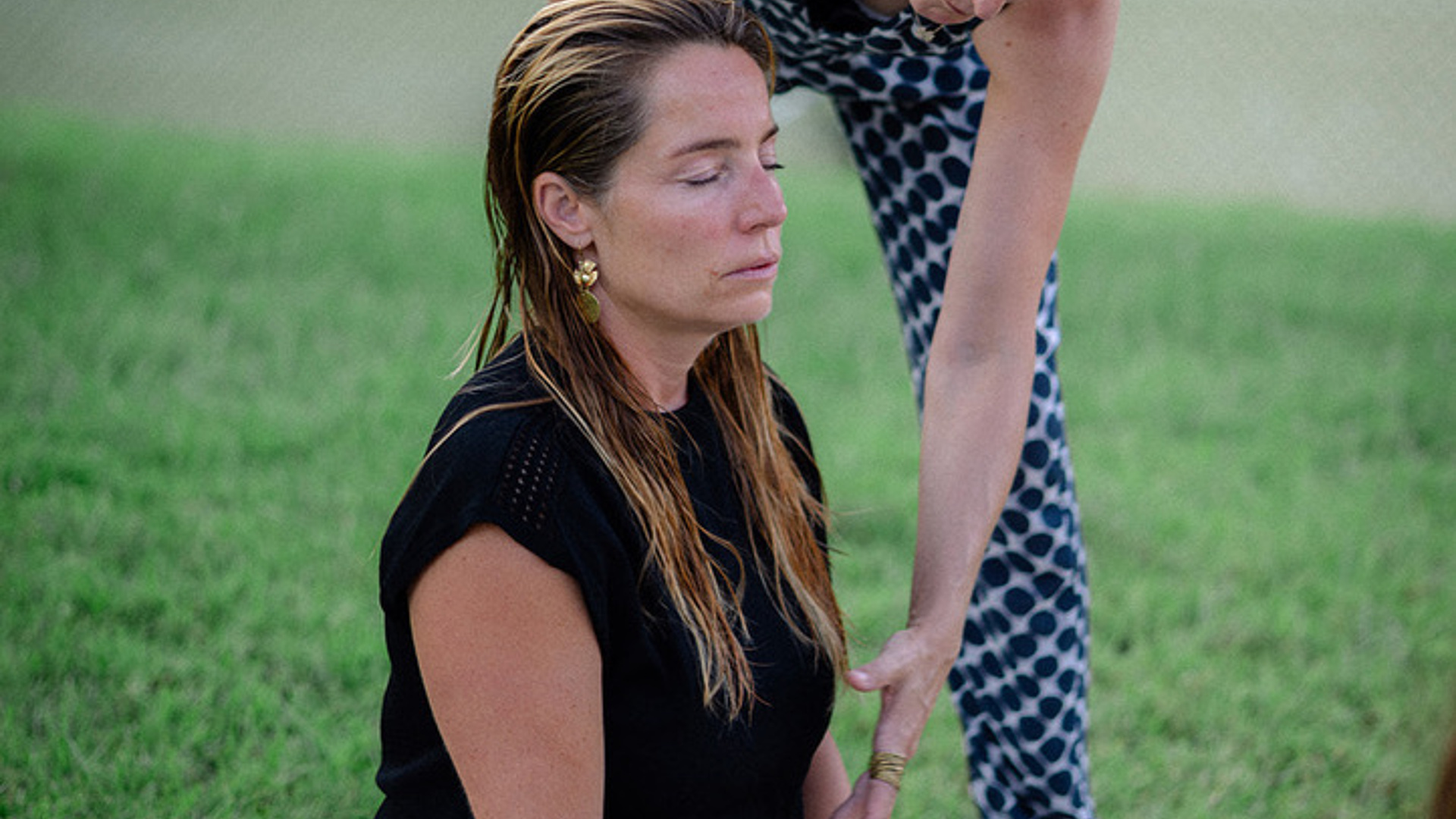 Gast sitzt entspannt auf der Wiese während einer Yoga-Session mit Coachin Hemma