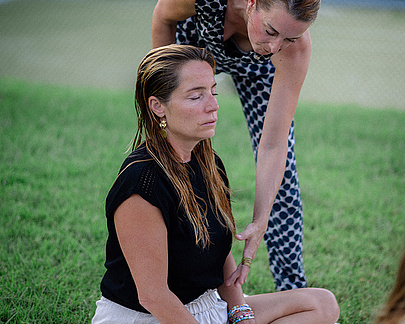 Gast sitzt entspannt auf der Wiese während einer Yoga-Session mit Coachin Hemma