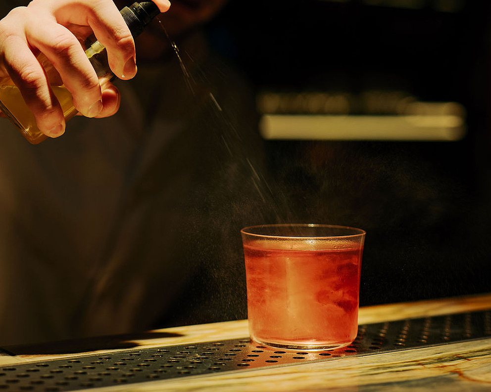 Cocktail wird vom Barkeeper im dunklen Ambiente des Restaurants Beletage hergerichtet